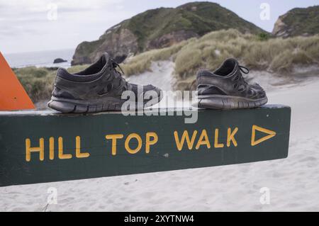 Schuhe auf dem Schild mit der Aufschrift „Hill Top Walk“ laden zu einer Wanderung ein Stockfoto