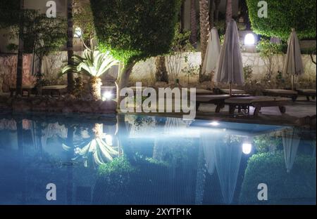 Blauer Wasserpool und grüne Palmen mit Straßenlaternen in der Nacht ohne Leute in scharm el sheikh ägypten Stockfoto