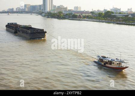 Ein kleines Schlepper zieht einen großen Lastkahn auf den Chao Phraya River in Bangkok, Thailand, Asien Stockfoto