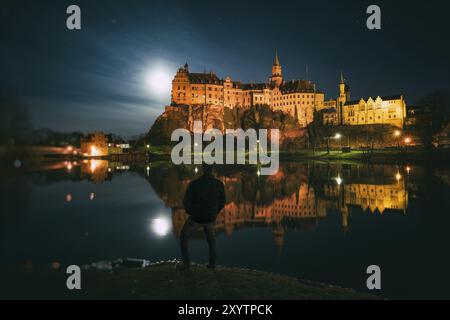 Die Hohenzollern in Sigmaringen liegt direkt an der Donau, der Vollmond neben der Burg beleuchtet die Umgebung. Ein Mann steht Stockfoto