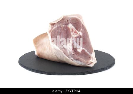 Frischer roher Schweinshaxe auf schwarzem Steinteller auf weißem Hintergrund Stockfoto