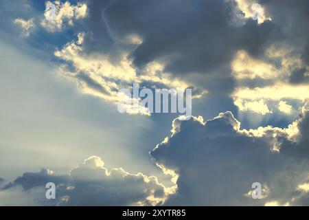 Glühende Sonne späht bei Sonnenuntergang in einem dämmerungsblauen Himmel in einem Natur- oder Wetterhintergrund mit Kopierraum durch die Wolken Stockfoto