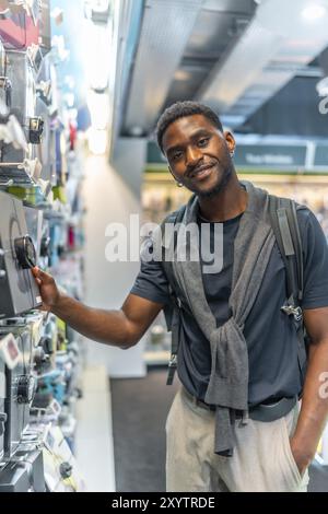 Vertikales Porträt eines hübschen afrikanischen jungen Mannes in einem Elektronikgeschäft Stockfoto