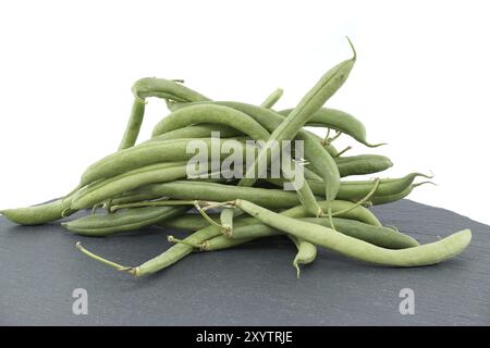 Haufen grüner Bohnen auf schwarzem Steintisch auf weißem Hintergrund mit voller Schärfentiefe. Bio- und Diätkost Stockfoto