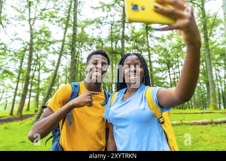 Zwei weibliche und männliche junge afrikanische Wanderer machen Selfie im Wald Stockfoto