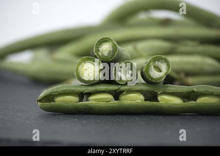 Ein Haufen geschnittener grüner Bohnen auf einem Tisch aus schwarzem Stein auf weißem Hintergrund. Bio- und Diätkost Stockfoto