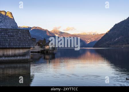 Grundlsee im Herbst bei Sonnenuntergang. Bootshäuser links, Berge im Hintergrund. Blauer Himmel, gutes Wetter. Grundlsee, Steiermark und Steirisches Salzkam Stockfoto