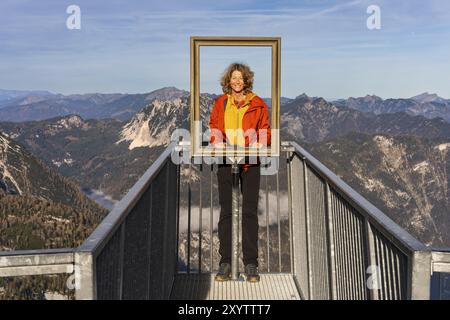 Ein Wanderer steht auf dem 5-Finger-Blickpunkt und schaut durch den Bilderrahmen. Blick vom Dachstein Krippenstein. Herbst, gutes Wetter. Einige Wolken Stockfoto