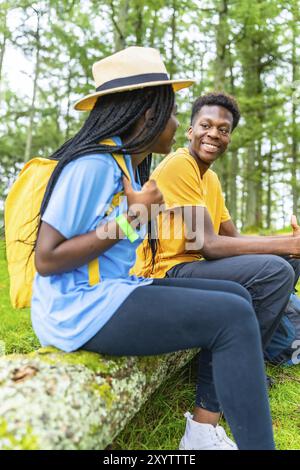 Vertikales Foto von zwei jungen afrikanischen Freunden, die während der Wanderung im Wald die Natur genießen Stockfoto