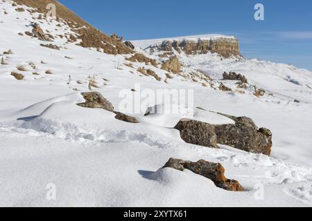 Die Landschaft der schneebedeckten kaukasischen Felsen am Gumbashi Pass. Schneebedecktes Plateau, das in den Tafelberg mit megalithischen Steinen in der führt Stockfoto