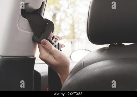 Die Hand einer Frau greift hinter ihren Sicherheitsgurt, um ihn anzulegen. Das Konzept des sicheren Fahrens von Frauen mit dem Auto Stockfoto