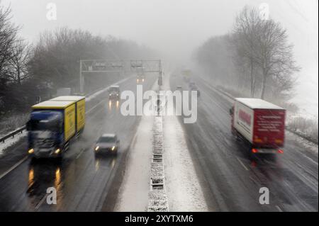 Lkw und Auto auf einer Autobahn bei Schnee und schlechter Sicht Stockfoto