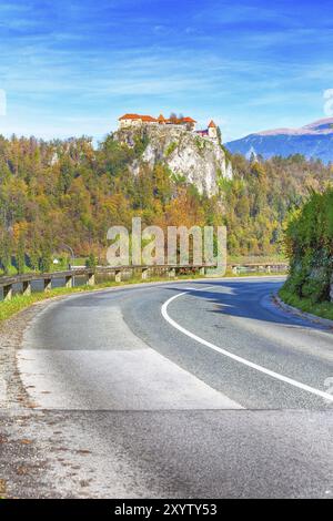 Mittelalterliche Burg auf dem Fels oben an der See Bled in Slowenien und Straße Perspektive, Herbst Bäume Wald Stockfoto