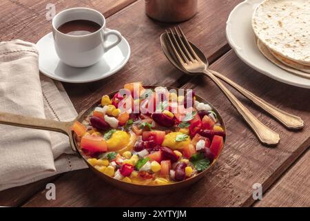 Mexikanisches Frühstück. Huevos Rancheros, die Spiegeleier, mit Pico de gallo Salat, heißer Schokolade und Tortillas auf einem dunklen rustikalen Holzhintergrund Stockfoto