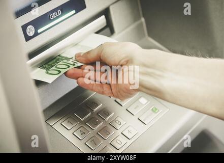 Junge Frau von einem Geldautomaten Geld abheben Stockfoto