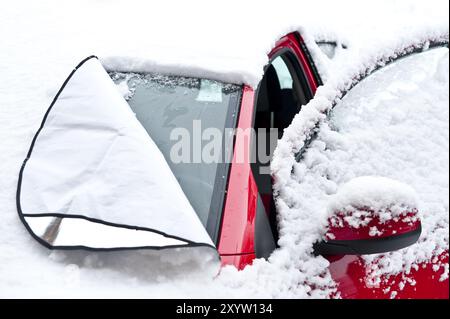 Rotes Auto unter einer frischen Schneedecke Stockfoto