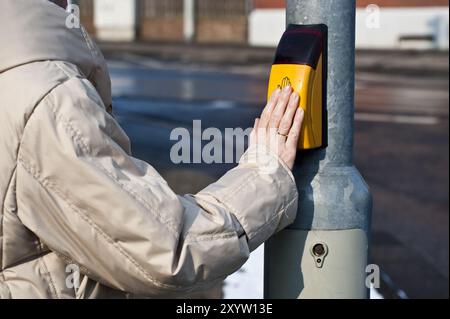 Die Person drückt die Hand auf den Knopf einer Ampelanlage Stockfoto
