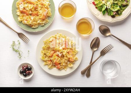 Ein Foto von einem Teller mit Lachs Nudeln, Farfalle mit geräuchertem Lachs und Sahnesoße, Schuß von der Oberseite mit Wein und Salat Stockfoto