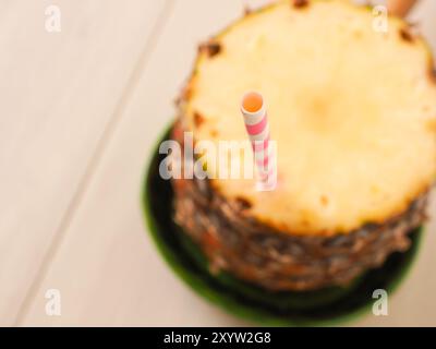 Frische organische Ananas mit einem Strohhalm auf einem Holztisch, selektiver Fokus auf der Trinkhalm, Ansicht von oben Stockfoto