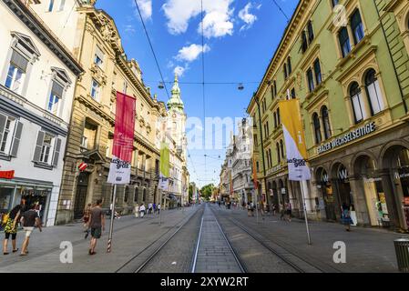 Österreich, 06 19 2016 : Blick auf die Herrengasse Hauptstraße im Stadtzentrum, Touristen laufen auf der Einkaufsstraße. Kirche im Hintergrund links, Europa Stockfoto