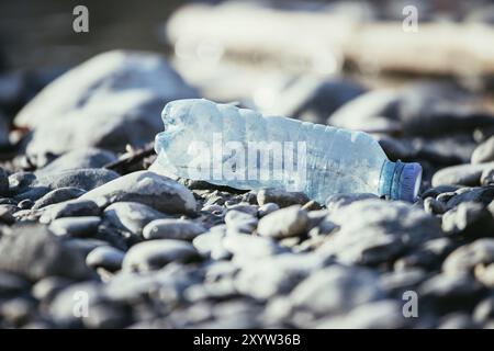 Plastikflasche liegt auf dem steinigen Strand, Umweltverschmutzung Stockfoto
