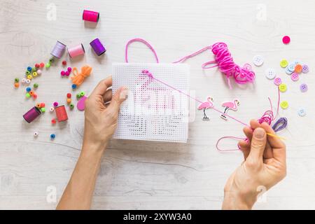 Nahaufnahme Person Kreuzstich Stickerei mit floss-Garn mit dekorativen Elementen Stockfoto