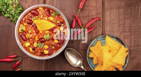 Ein Panorama der mexikanischen Küche. Chili con Carne, Chili, Koriander Blätter, und Nachos, Schuß von der Oberseite in einem dunklen Holzmöbeln im Landhausstil Hintergrund Stockfoto