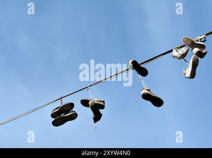 Entsorgte Schuhe hängen an einer Schnur im Stockfoto