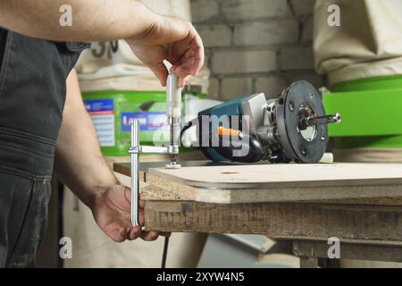 Close Up Master klemmt das Werkstück mit einer dvp-Klemme an der Werkbank und auf dem Hintergrund liegt der Handfräser von Carpentry Stockfoto