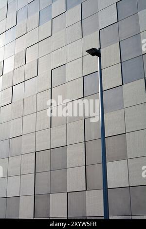 Detail der Fassade eines modernen Gebäudes in Magdeburg. Die Fassade ist mit quadratischen Steinplatten in einem Schachbrettmuster bedeckt. Im Vordergrund steht ein s Stockfoto