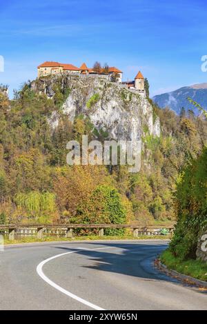 Mittelalterliche Burg auf dem Fels oben an der See Bled in Slowenien und Straße Perspektive, Herbst Bäume Wald Stockfoto