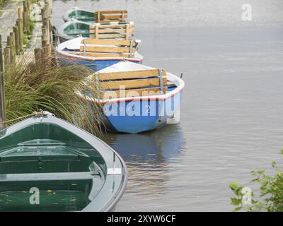 Ruderboote an einem Holzsteg an einem ruhigen See, umgeben von Gras, Bad Zwischenahn, ammerland Stockfoto