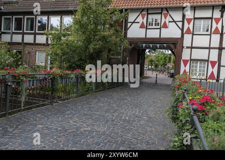 Ein historisches Fachwerkhaus mit Blumenbeeten entlang eines Kopfsteinpflasterwegs, gefüllt mit bunten Blüten und einer einladenden Atmosphäre, Gemen, Muensterla Stockfoto