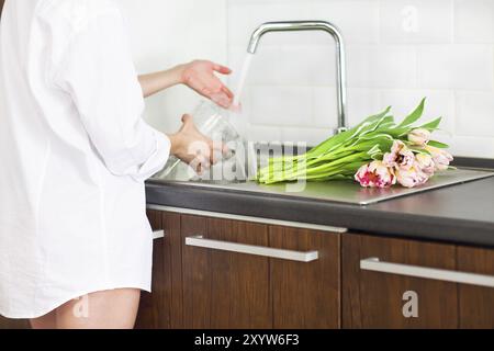 Junge Frau spülen und Blumen schneiden und gießt Wasser in der Vase im Spülbecken. Nahaufnahme Stockfoto