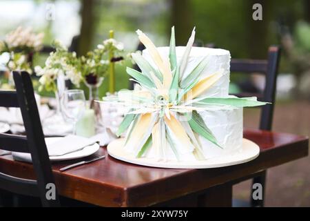 Wunderschöne Hochzeitstorte mit Blumen auf dem Tisch, im Freien Stockfoto