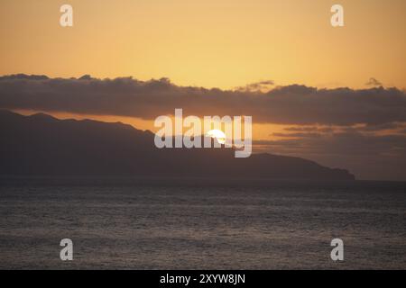Meer mit untergehender Sonne hinter Wolken Stockfoto