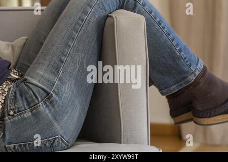 Frau in Hosen, die in einem Sessel liegt Stockfoto