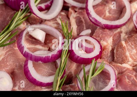 Schweinefleisch vom Hals mit roten Zwiebeln in Scheiben geschnitten, Fleisch auf einem Schneidebrett unter Marinieren in Zwiebeln und Gewürzen Stockfoto