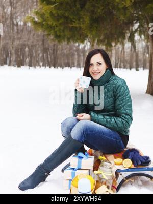 Glückliche junge schwangere Frau Spaß im Winter Park heißen Tee trinken Stockfoto