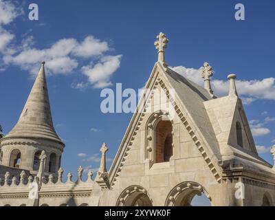 Historisches Gebäude mit turmähnlichen Strukturen und kunstvollen Steindekorationen unter blauem Himmel, budapest, donau, ungarn Stockfoto