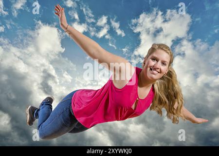 Mädchen fliegt lachend hoch in Wolken vor blauem Himmel Stockfoto