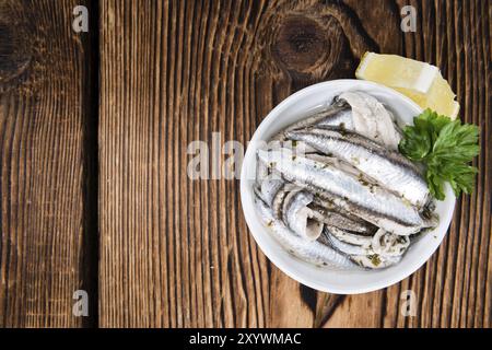 Eingelegte Anchovis mit Kräutern (Nahaufnahme) auf hölzernen Hintergrund Stockfoto