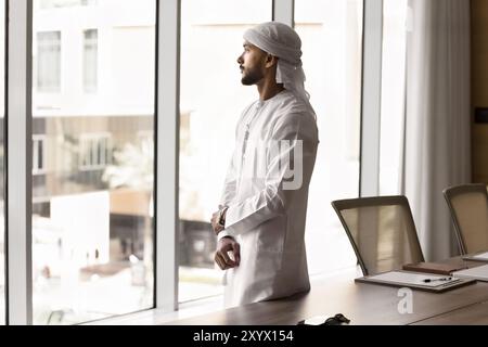 Nachdenklicher arabischer Exekutivmann, der aus dem Fenster schaut Stockfoto