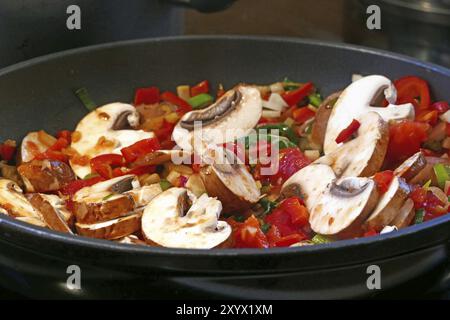 Gebratenes Gemüse, Pilze, Paprika, Zwiebeln, Lauch in einer schwarzen Pfanne verrühren Stockfoto