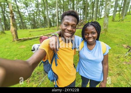 Afrikanische Freunde lächeln beim Selfie-Wandern im Wald Stockfoto