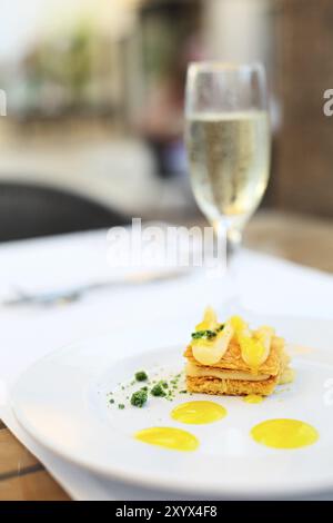 Milfey Kuchen mit Zitronencreme auf der Platte. Prosecco auf dem Hintergrund Stockfoto