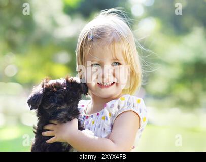 Niedlichen Mädchen umarmt Hund Welpen im Freien. Freundschaft und Pflege-Konzept Stockfoto