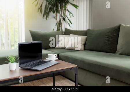 Arbeiten von zu Hause aus, Arbeitsplatz, Desktop, Remote-Work-Konzept, graues Notebook, Schwarzer leerer leerer Bildschirm auf Holztisch mit weißer Tasse Kaffee, gree Stockfoto