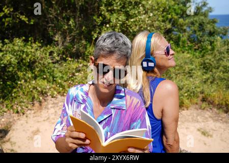 Eine Tochter und ihre Mutter hören Musik und lesen ein Buch. Freizeit in der Familie Stockfoto