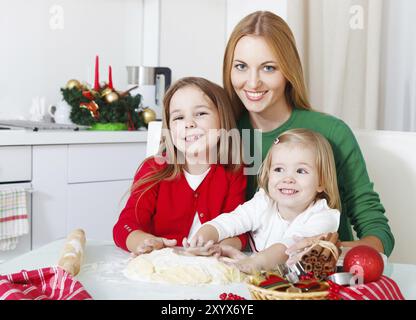 Zwei kleine Mädchen mit Mutter Backen Weihnachtsplätzchen in der Küche Stockfoto